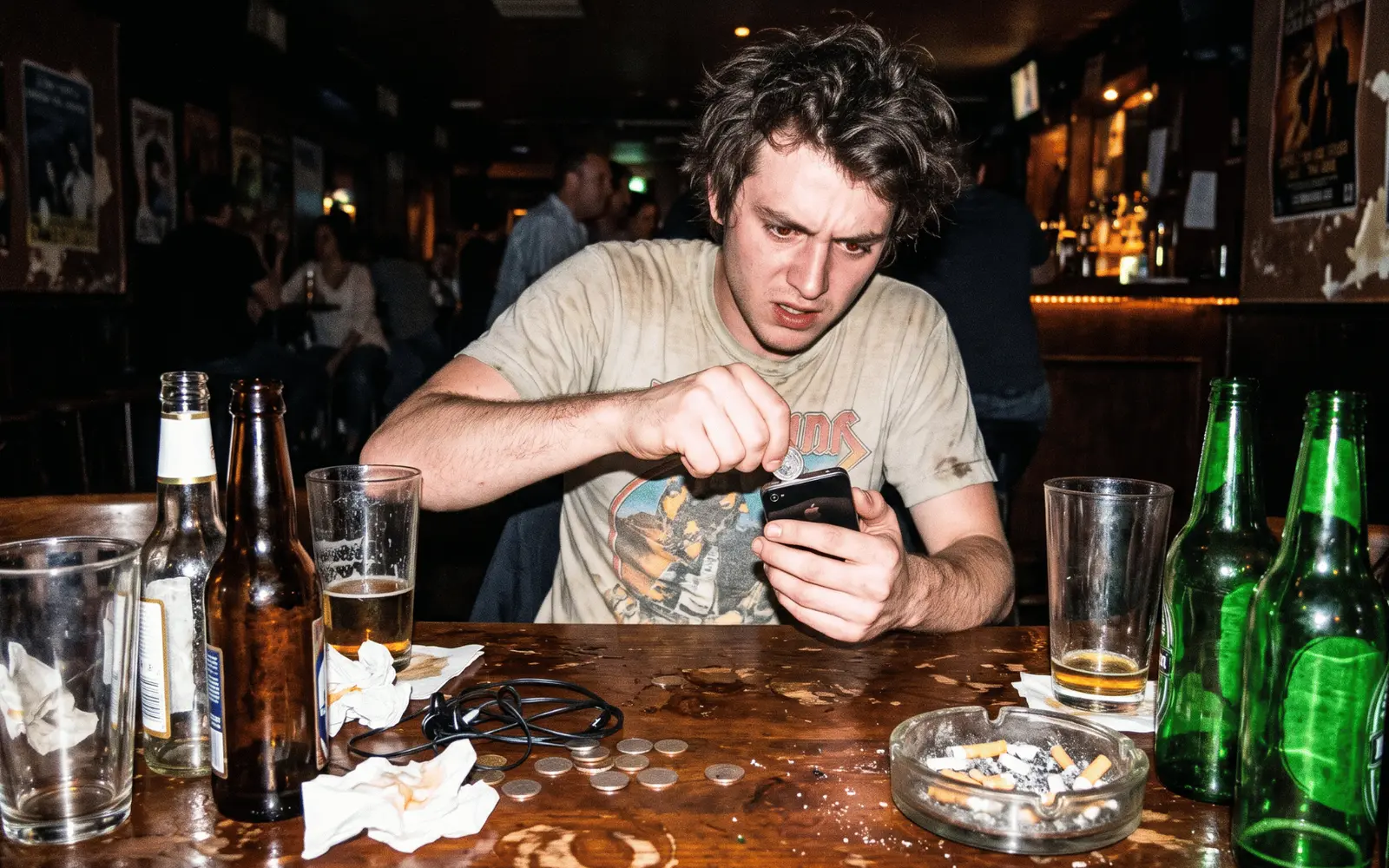 Mostrador de tienda a medianoche, un teléfono iluminado con una conversación de WhatsApp abierta entre cajas y facturas desordenadas, flash directo y grano.